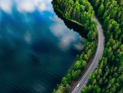 Aerial view of a road winding through a forest and a lake